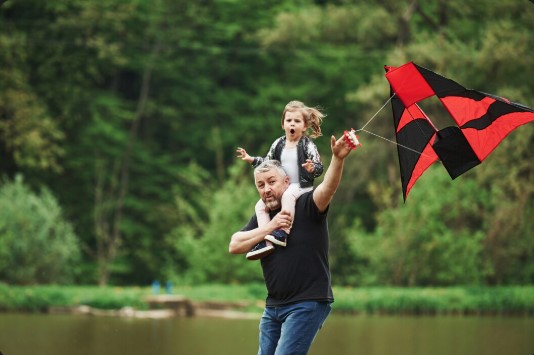Father and daughter playing with a red kitten